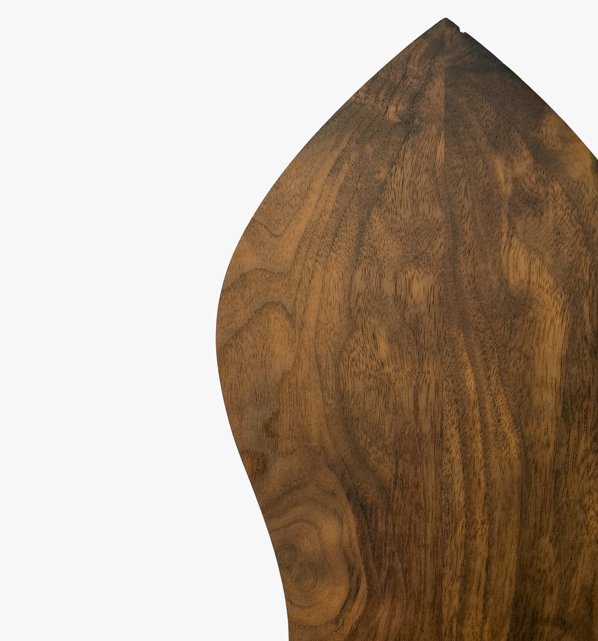 The pointed top of a walnut wall piece, showing its deep grain