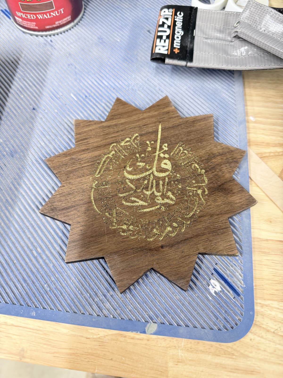 A walnut star with gold-filled calligraphy on the workshop mat during making